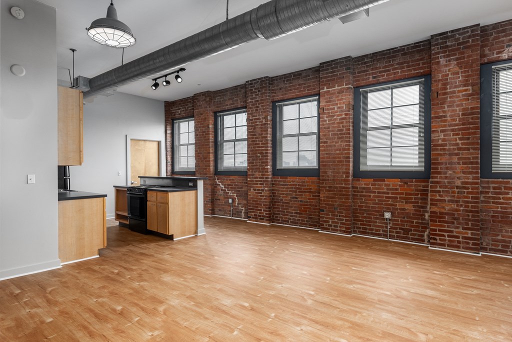 an empty living room with a brick wall and wood floors at Lofts at Lafayette Square Apartments, Saint Louis, MO