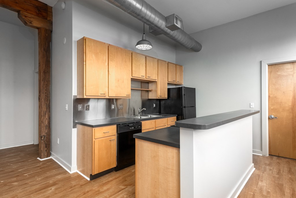 an empty kitchen with wooden cabinets and black counter tops at Lofts at Lafayette Square Apartments, Saint Louis, MO