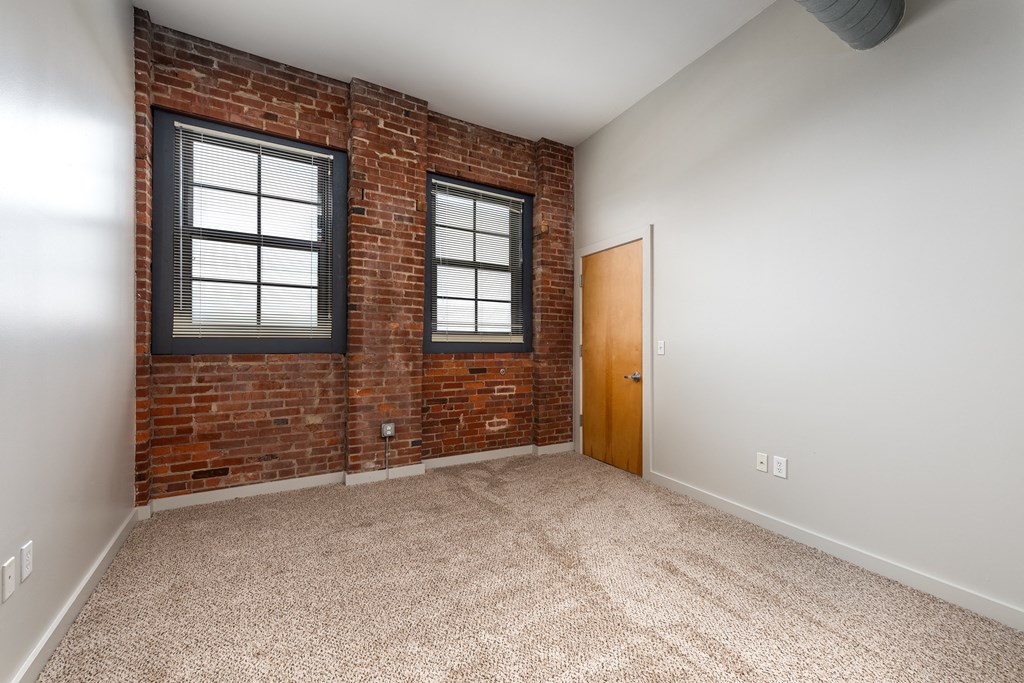 an empty room with a brick wall and a door and a window at Lofts at Lafayette Square Apartments, Missouri, 63104