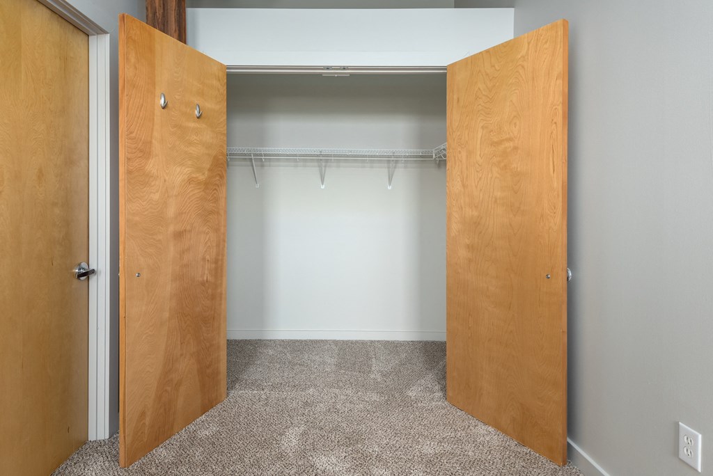 an empty closet with two wooden doors and a white wall at Lofts at Lafayette Square Apartments, Saint Louis
