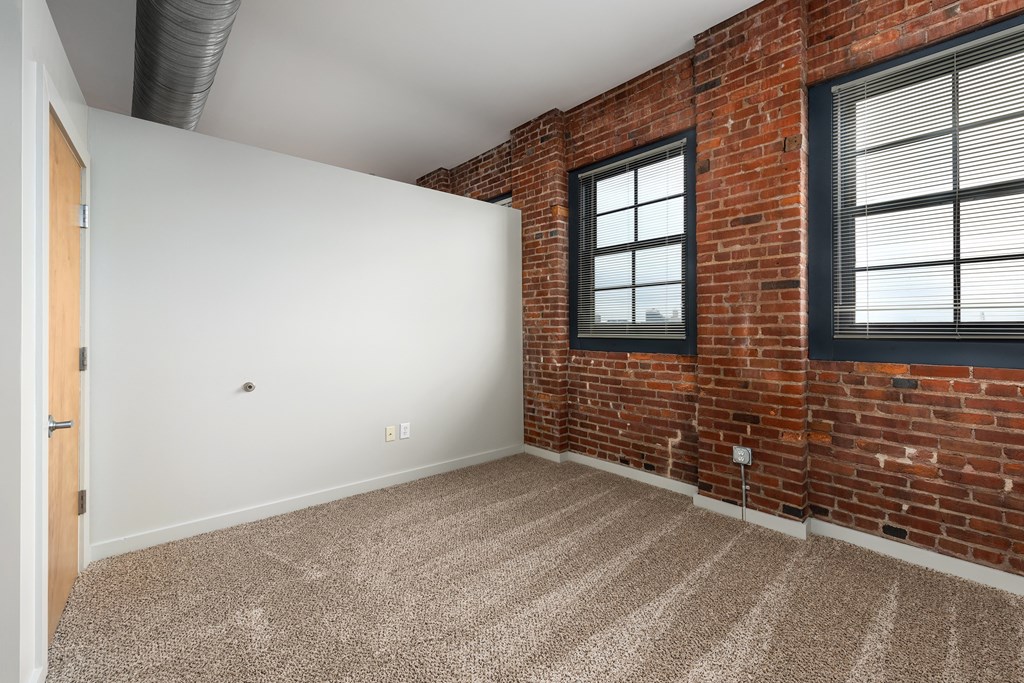 A room with a brick wall and carpeted floor at Lofts at Lafayette Square Apartments, Saint Louis, Missouri