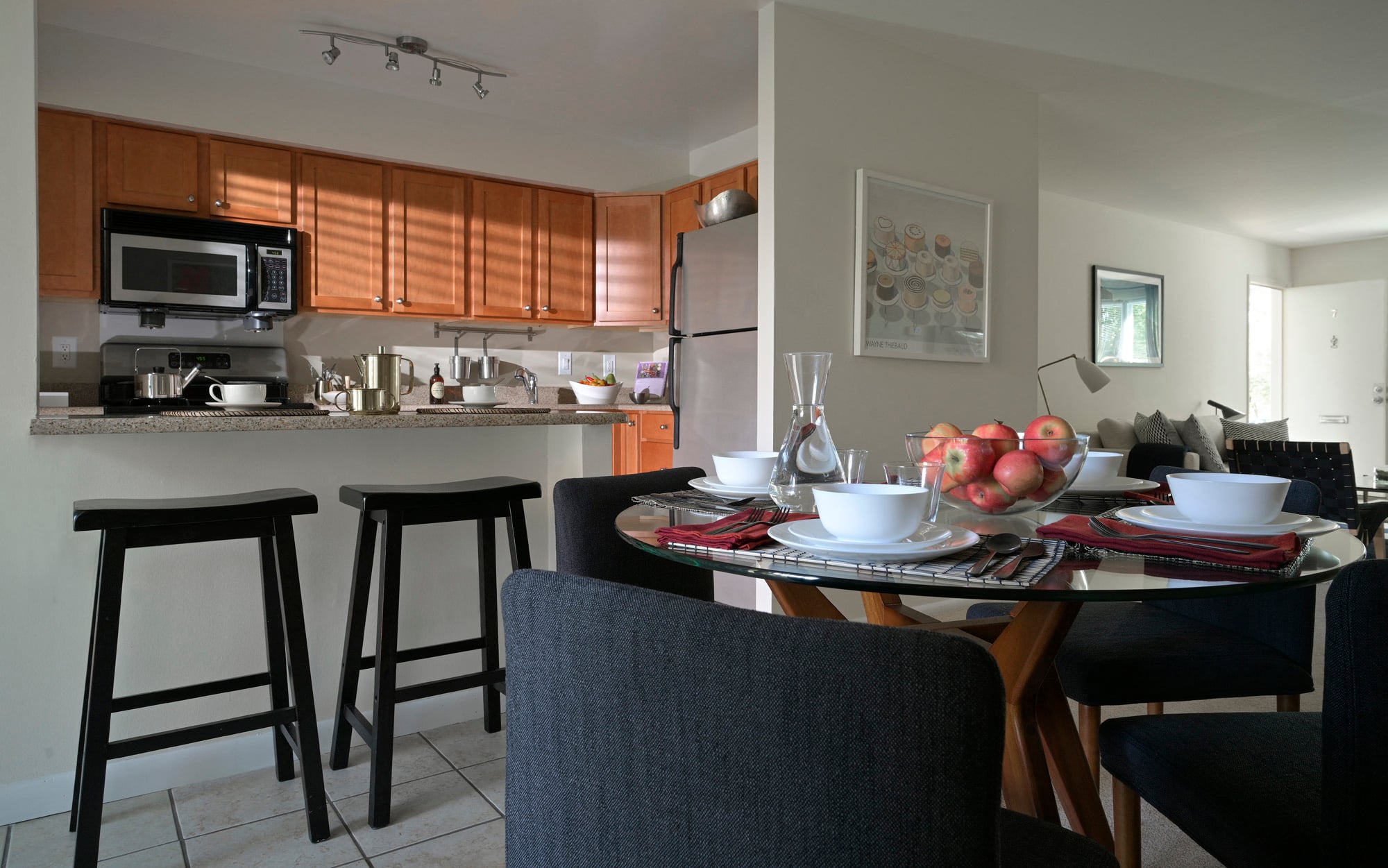 A kitchen with a table set for two and a refrigerator.