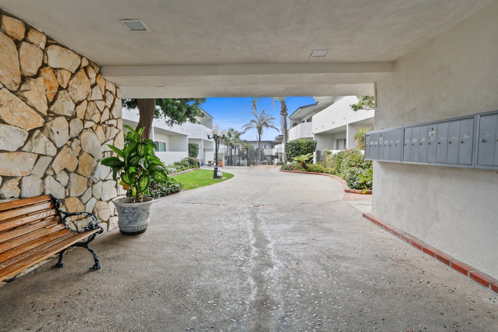 a walkway with a bench and a stone wall on the side of a building