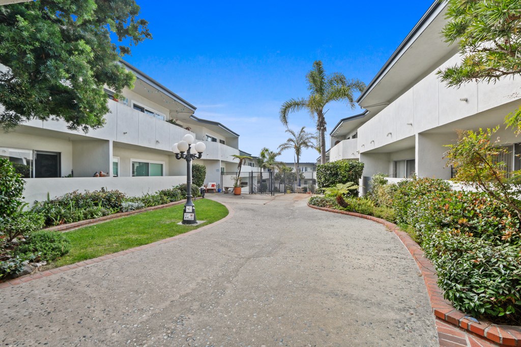 the pathway between the apartments is surrounded by plants and trees