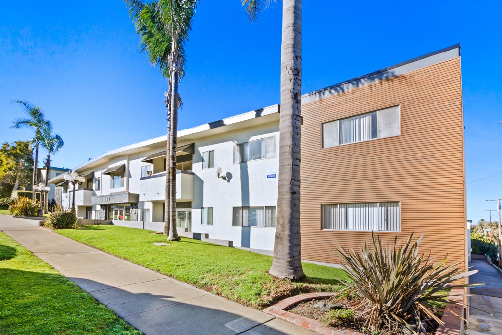 a building with a sidewalk and palm trees in front of it