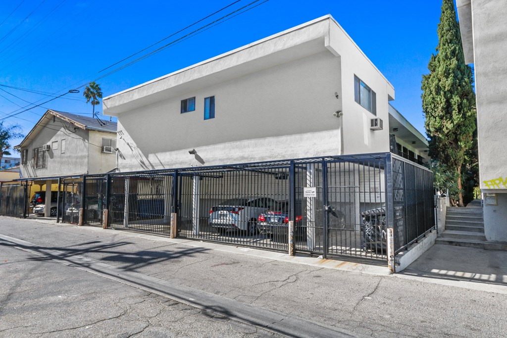 a white building with a gate and cars parked in front of it