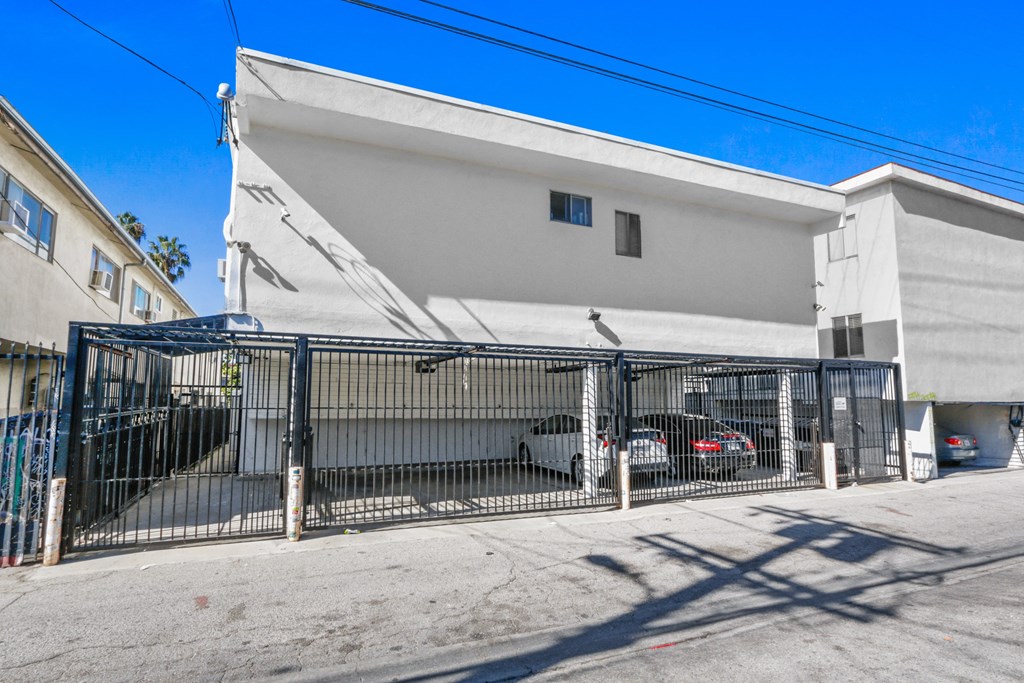 a white building with a gate and parked cars in front of it