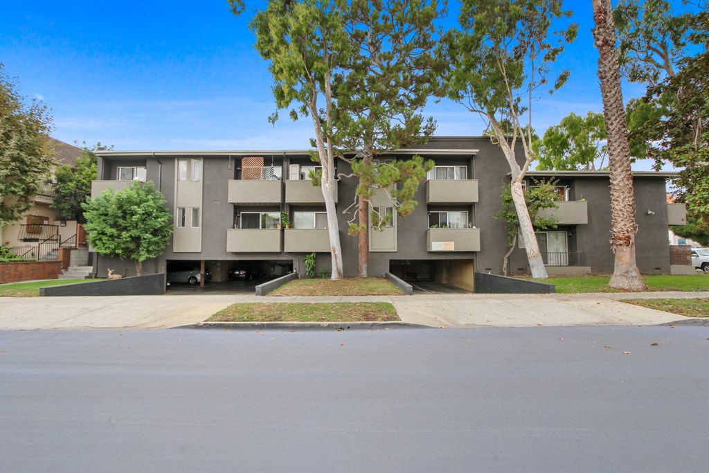 a gray apartment building with trees in front of it