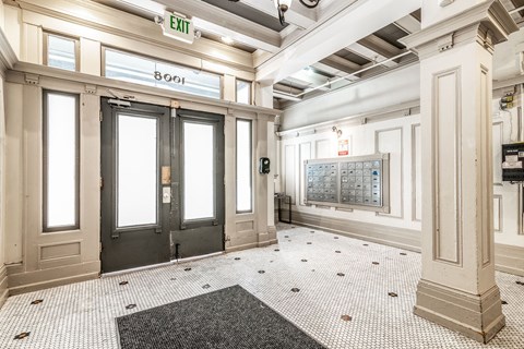 A hallway with a black and white checkered floor, a black door, and a white wall with a calendar on it.