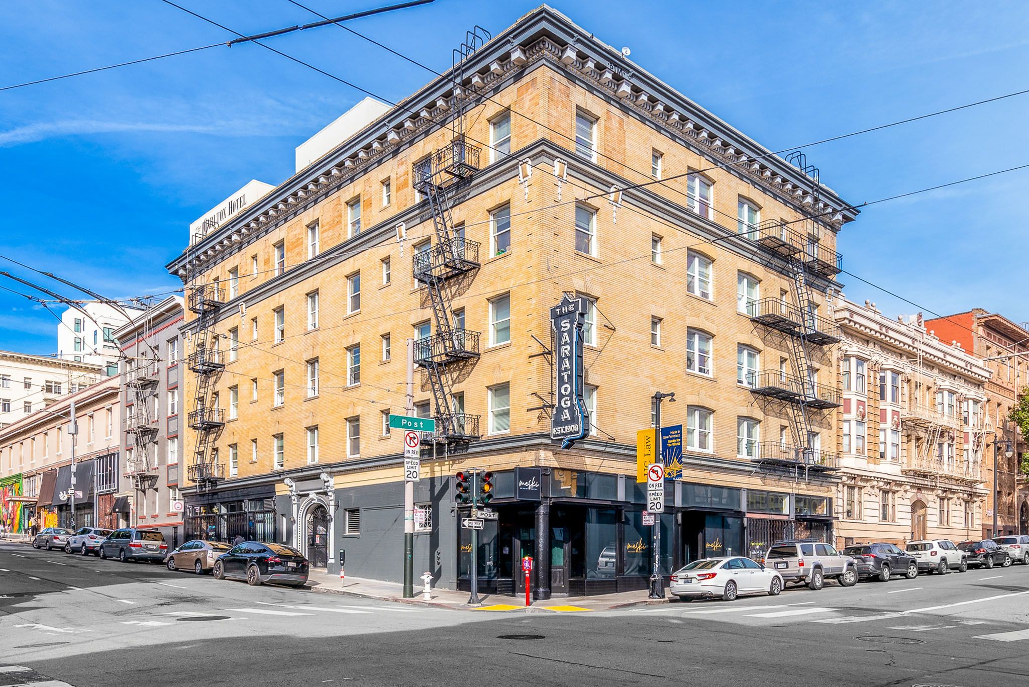 A street view of a city with a yellow building in the center.