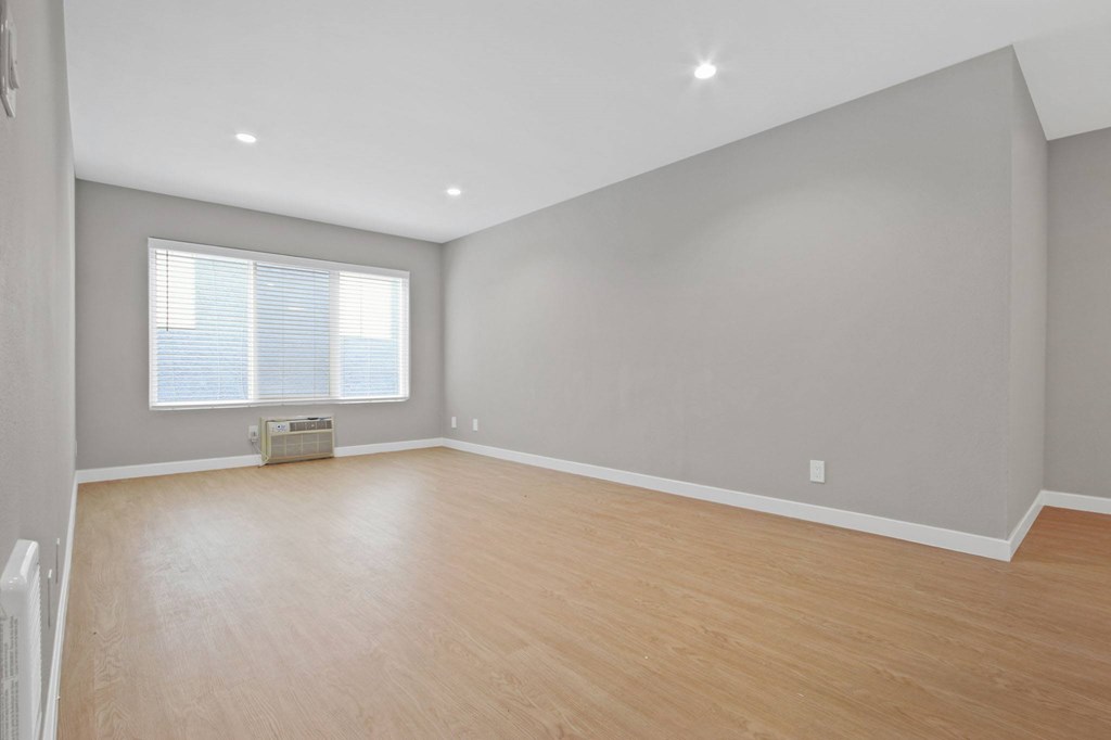 A room with wooden flooring and a window with blinds.