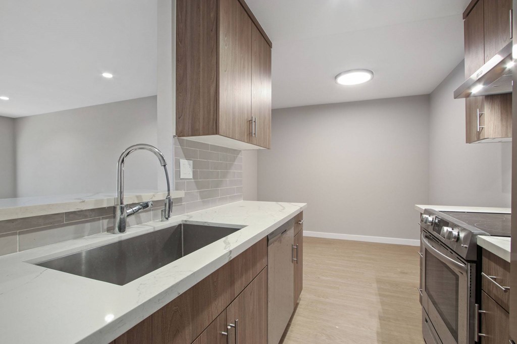 A modern kitchen with a stainless steel sink and wooden cabinets.