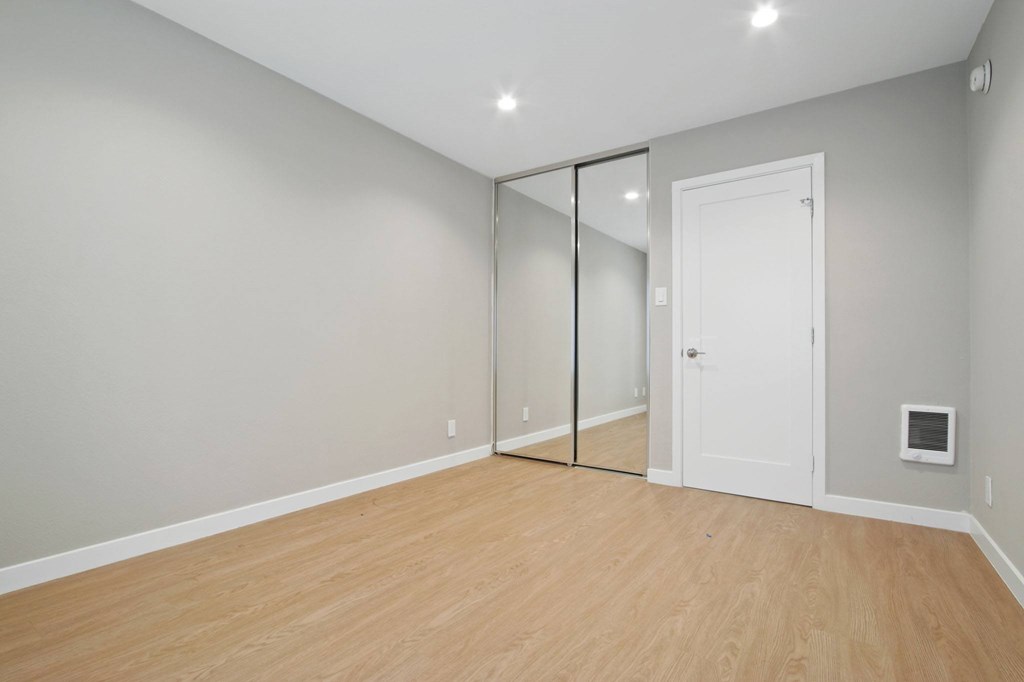 A room with a white door and a mirror on the wall.