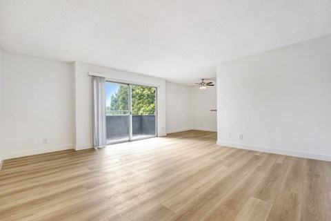A room with wooden flooring and a sliding glass door leading to a balcony.