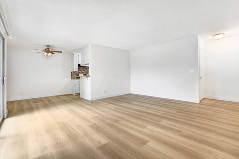 A room with a ceiling fan and wooden flooring.