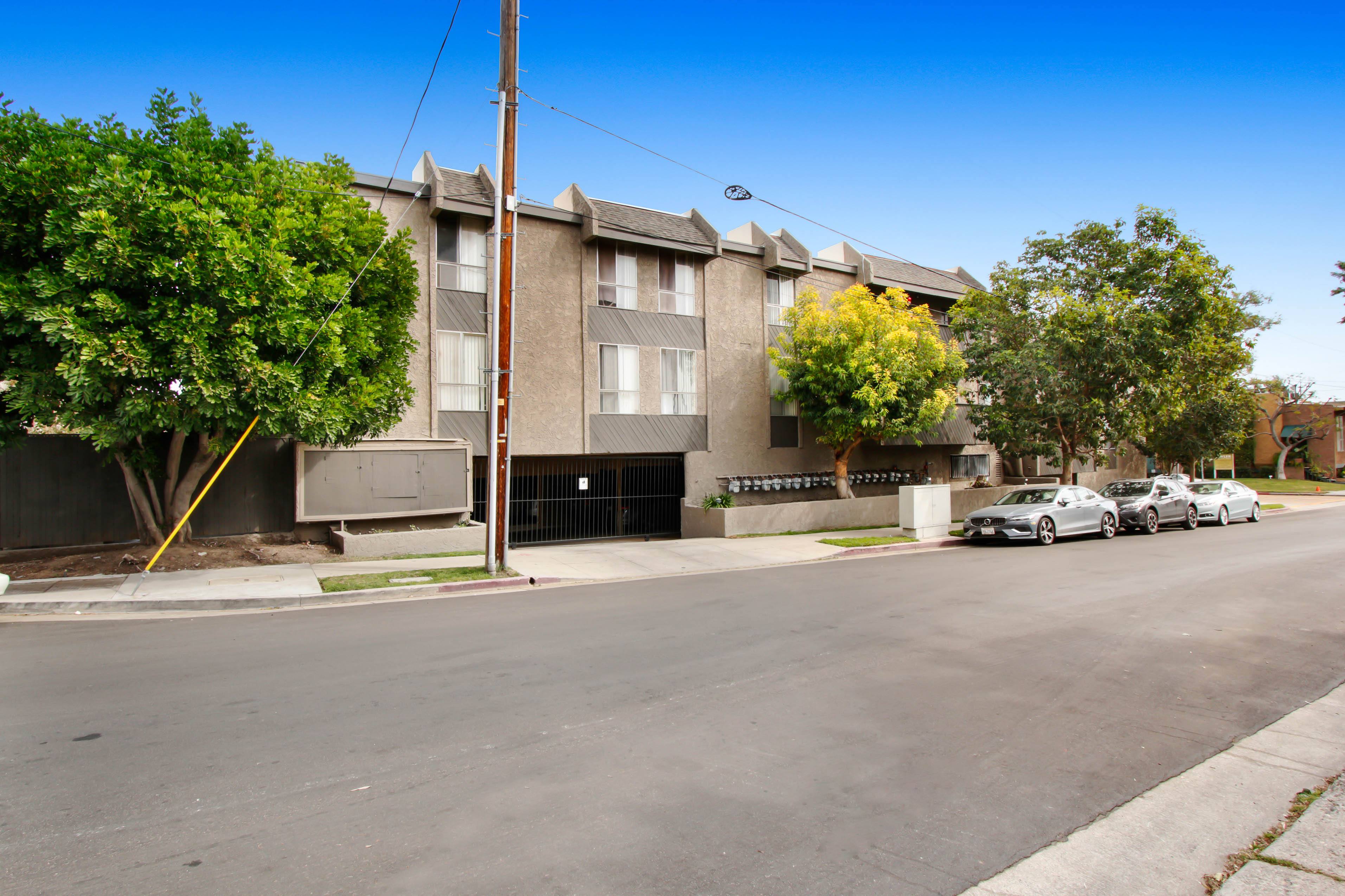 A street view of a residential area with apartment buildings and parked cars.