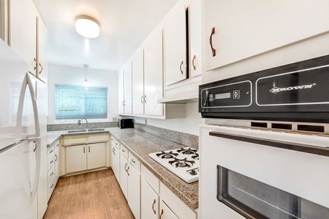 A modern kitchen with white cabinets and a black stove top oven.