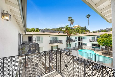 A balcony with a pool and palm trees in the background.