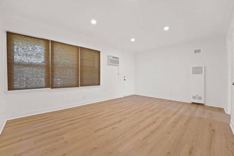 A room with wooden flooring and a window with blinds.