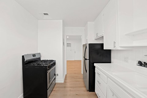 A black stove and refrigerator in a white kitchen.