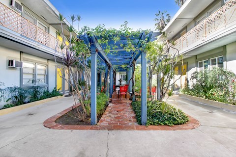 A walkway with a blue canopy and plants on either side.