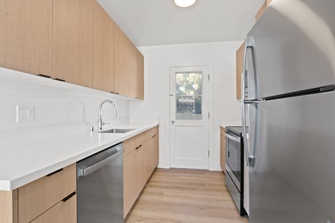 A kitchen with a refrigerator, sink, and cabinets.
