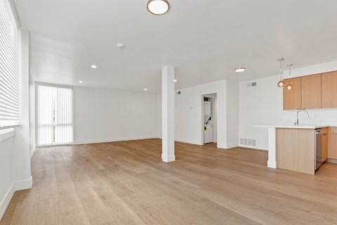 A spacious room with wooden flooring and white walls.