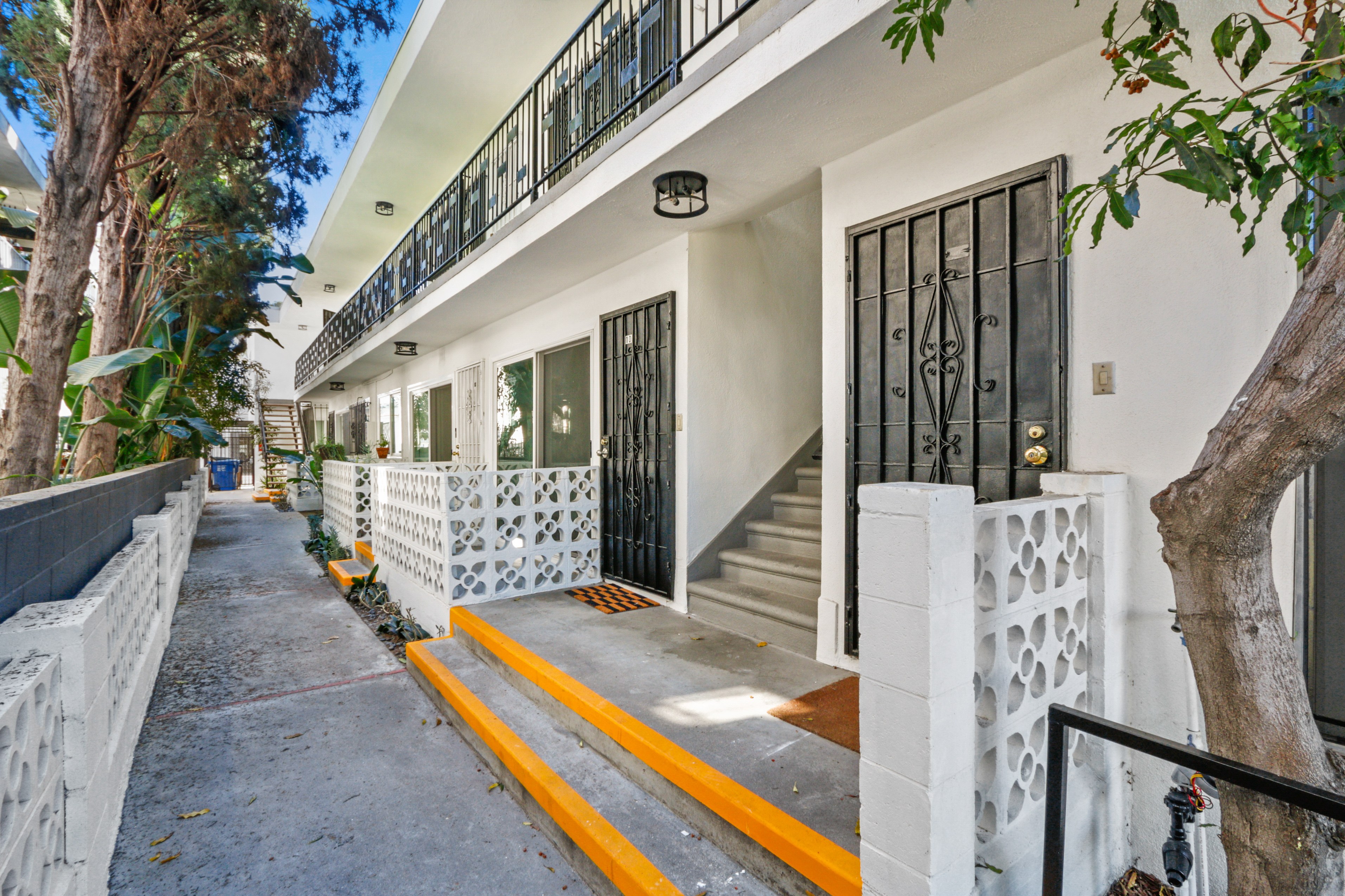 A white building with a black gate and a yellow line on the sidewalk.
