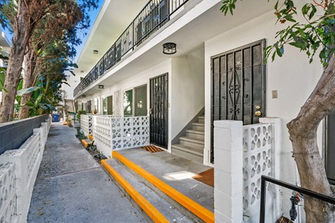 A white building with a black gate and a yellow line on the sidewalk.