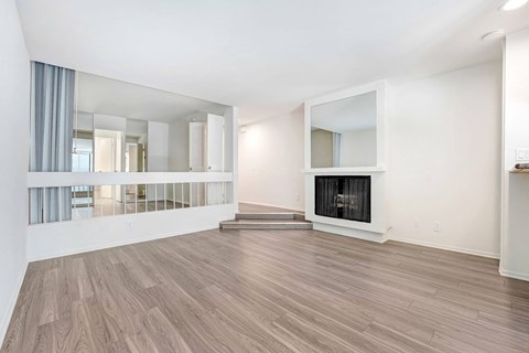 A spacious room with wooden flooring and a fireplace.