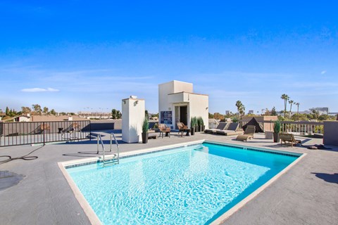 A swimming pool in a backyard with a white building in the background.