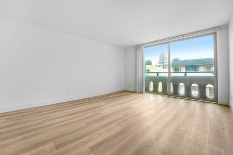 A room with wooden flooring and a large window overlooking a building.