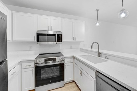 A modern kitchen with white cabinets and stainless steel appliances.