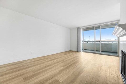 A room with wooden flooring and a large window with a view of the outside.