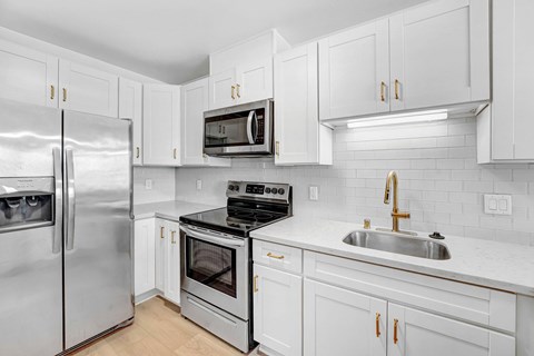 A modern kitchen with white cabinets and stainless steel appliances.