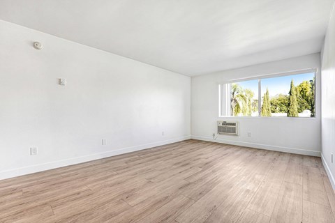 Empty room with wooden flooring and a window.