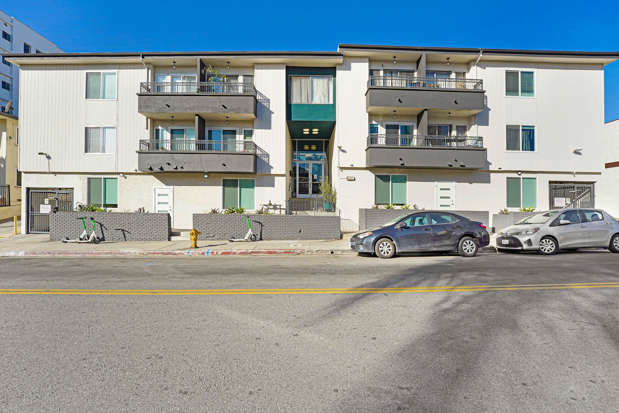 Two cars parked in front of a white apartment building.