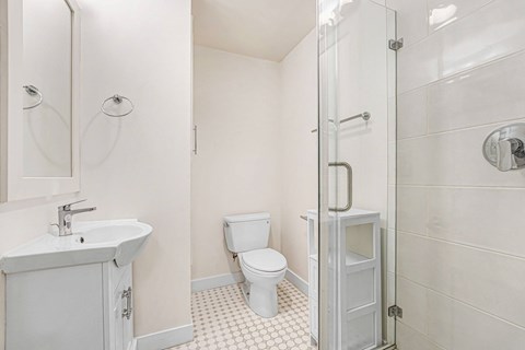 A white bathroom with a toilet, sink, and shower.
