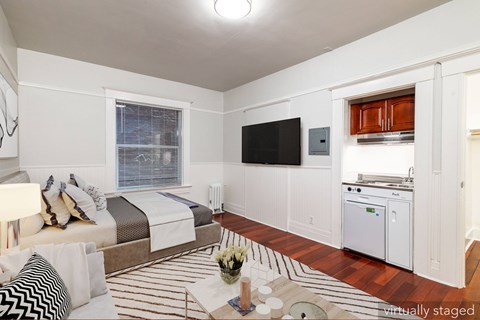 A bedroom with a bed, a television, and a striped rug.