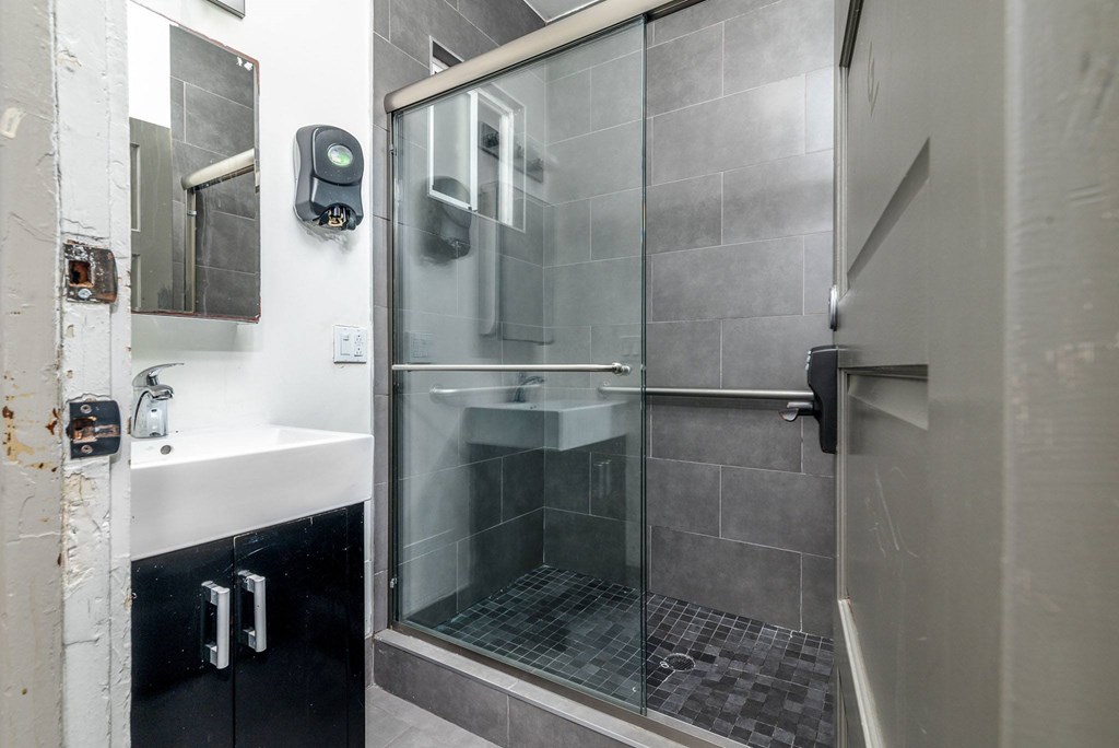 A modern bathroom with a glass shower door and a white sink.