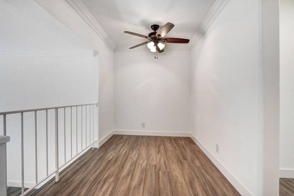 an empty living room with a ceiling fan and white walls