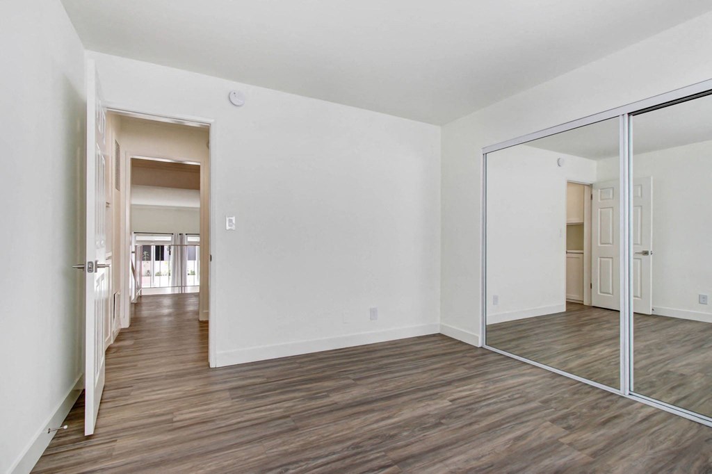 a living room with a mirror and a hallway to a bedroom