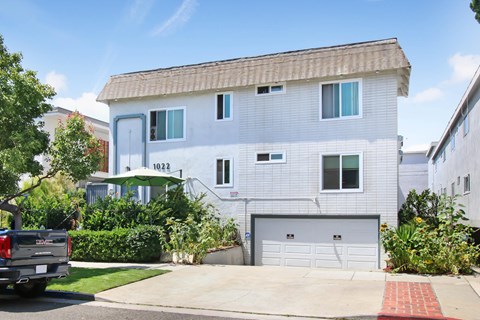 A white two-story house with a garage and a truck parked in front.