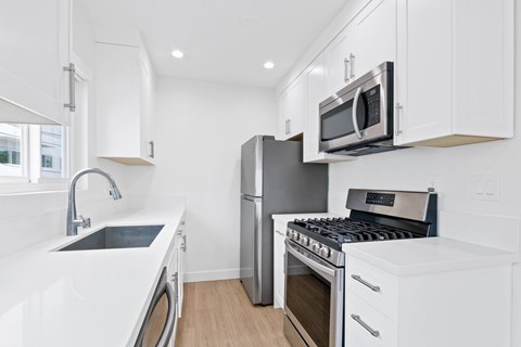 A modern kitchen with white cabinets and stainless steel appliances.