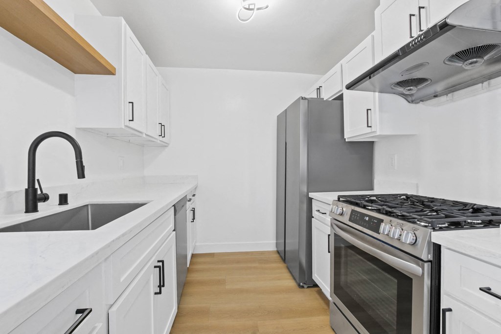 A modern kitchen with white cabinets and stainless steel appliances.
