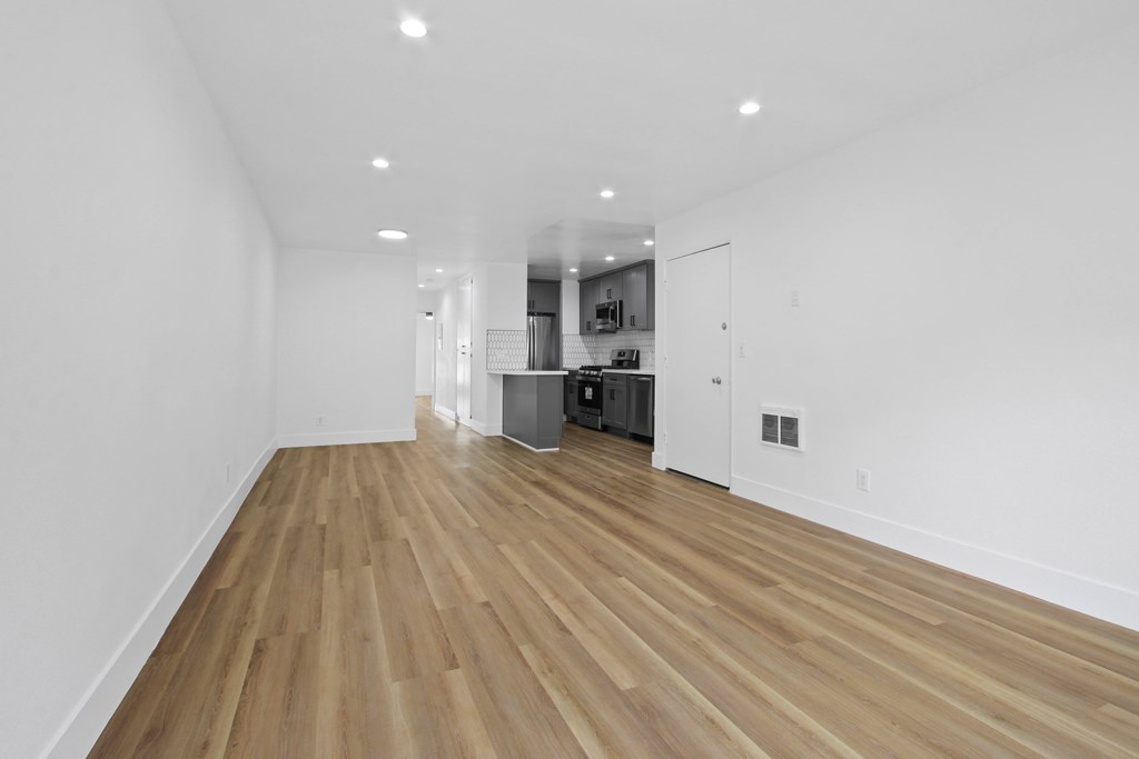 A long, empty room with wooden floors and white walls.