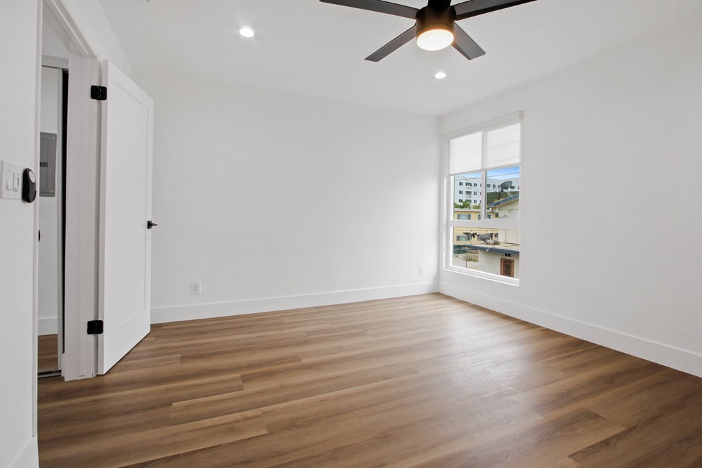 A room with a ceiling fan and wooden flooring.