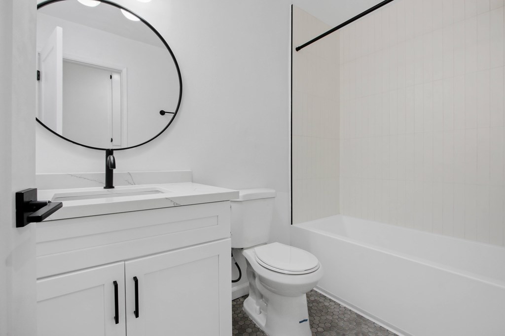 A white toilet sits in a bathroom next to a sink and a mirror.