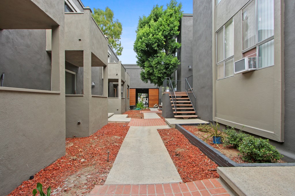 A pathway with red bricks leads to a building with a brown door.