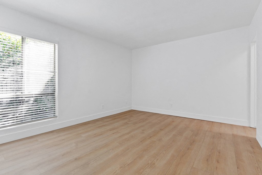 an empty room with wood floors and a large window